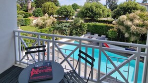 Un espacio al aire libre cubierto con una piscina, barandillas blancas y una mesa con un libro.