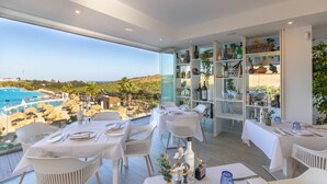 Un espace repas avec des tables préparées pour deux personnes, offrant une vue sur une piscine et un paysage pittoresque.