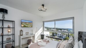 Une chambre moderne avec une grande fenêtre, un lit avec des oreillers, un bureau et une bibliothèque.