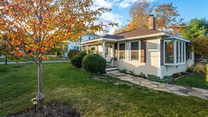 A single-story house with a front porch, a covered entryway, and a small attached garage. - Charming Cottage Steps from Hulls Cove Beach & Entrance to Acadia! (Bar Harbor)