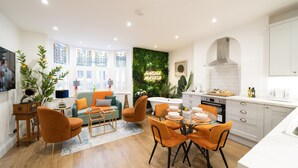 Una cocina moderna con comedor, muebles blancos y una pared decorada en verde.