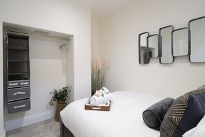 A neatly organized bedroom with a bed, a built-in wardrobe, and a wall-mounted mirror.
