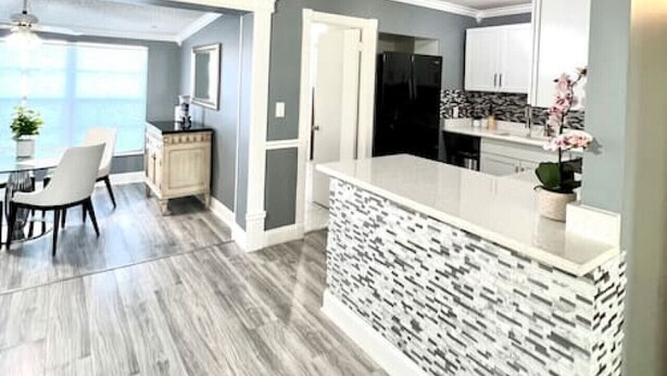 A modern kitchen with a central island, grey walls, and a dining area with a view. - Spacious & Luxurious Villa - Large Fenced Backyard (West Palm Beach)