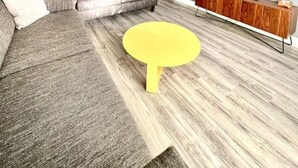 A modern living room with a grey sectional sofa, a yellow coffee table, and a wooden TV stand. - Spacious & Luxurious Villa - Large Fenced Backyard (West Palm Beach)