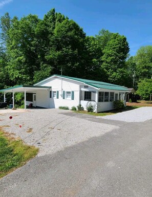 A single-story white building with a green roof, numbered 383, featuring a covered porch and a small attached structure.