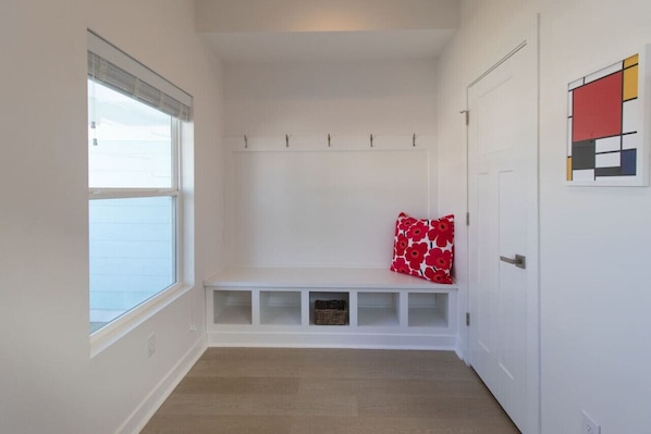 A hallway with a bench, a coat rack, and a door.