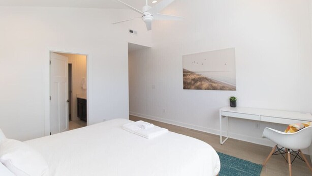 Une chambre moderne avec un lit, un bureau et un ventilateur de plafond.