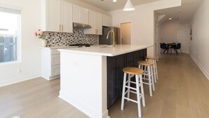 Une cuisine moderne avec des meubles blancs, un grand îlot central doté de tabourets et un pare-feu décoratif.