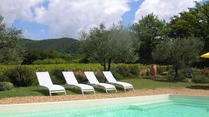Una piscina con agua cristalina y sillas de descanso blancas.