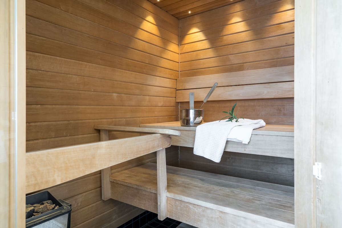 Eine Sauna mit Holzwänden, einer Sitzbank, einem Handtuch und einem Eimer.