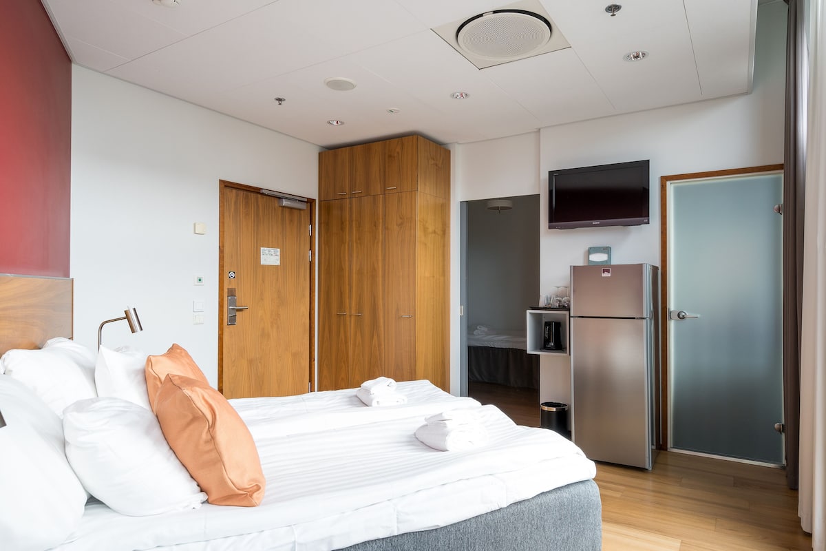 Ein Hotelzimmer mit einem Bett, einem Holzschrank, einem Fernseher und einem Kühlschrank.
