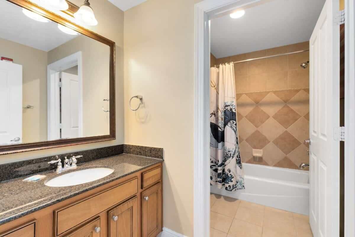 A bathroom with a sink, mirror, and shower area.