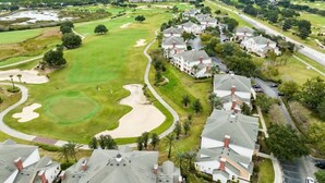 A golf course with sand bunkers, a clubhouse, and residential buildings. - 3BR Golf View w/ $50 Theme Park Credit (Kissimmee)