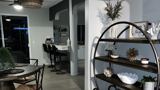 Una cocina moderna con comedor, que incluye una mesa redonda, sillas, una araña y un estante de metal decorativo.