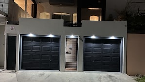 Una casa moderna de dos pisos con dos puertas de garaje, una pequeña entrada y una escalera visible que conduce al nivel superior.