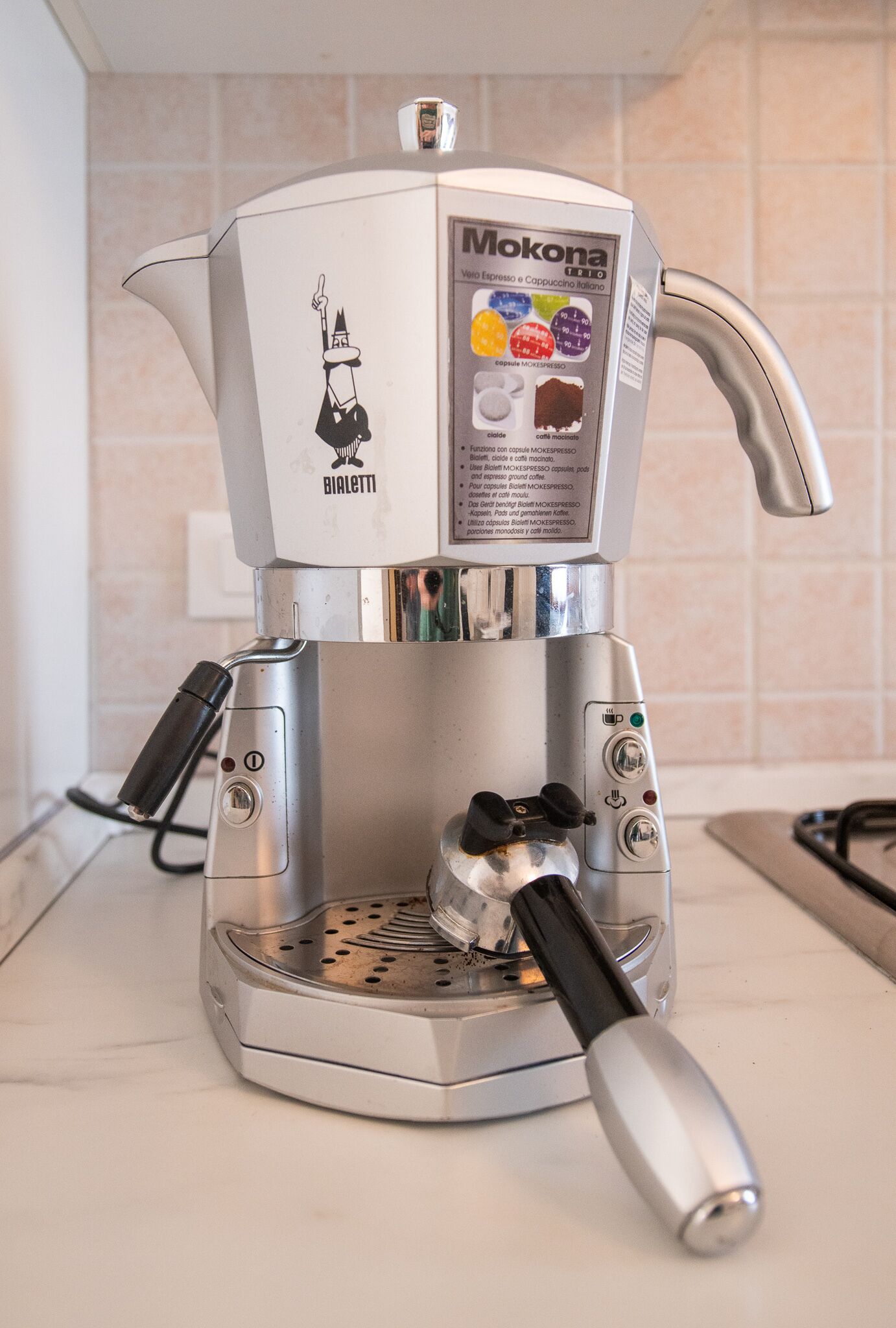 Eine Kaffeemaschine mit einer Beschriftung, einem Ausguss und einem Siebträger.