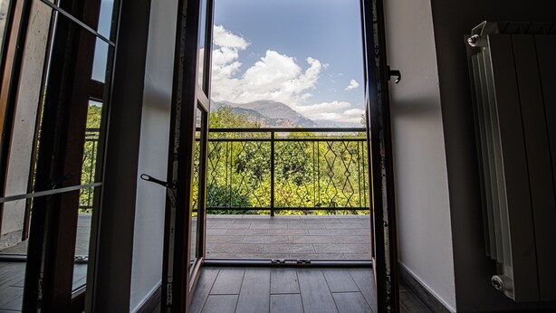 An open balcony with a view of mountains and trees.