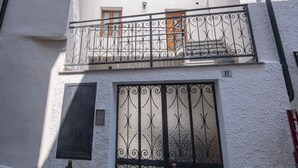 A two-story building with a balcony, a metal gate, and a clear sky.
