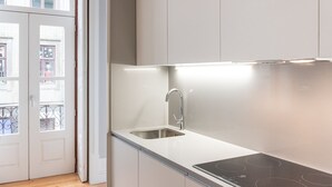 Une cuisine moderne dotée d’un évier en acier inoxydable, d’un robinet élégant et d’une plaque de cuisson à induction noire.