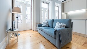 Un salon moderne avec un canapé gris, une petite table d’appoint blanche et un lampadaire.