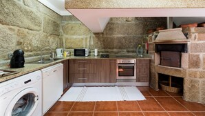 Une cuisine compacte avec des murs en pierre, un lave-linge, un four à micro-ondes, un grille-pain et un four encastré.