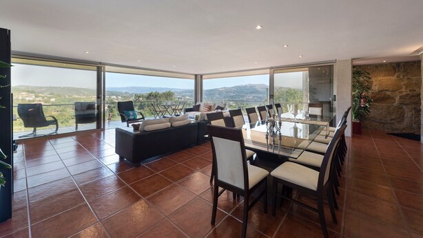 Un vaste espace de vie comprenant une table à manger en verre, des sièges confortables et une vue panoramique.
