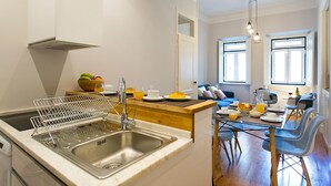 A modern kitchen with a built-in dishwasher, a dining area with a table set for breakfast, and a view of the living room.