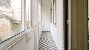 A narrow hallway with checkered flooring, white walls, and multiple windows.