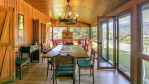 Un interior de madera con una mesa de comedor, sillas y una araña.