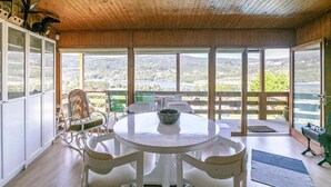 Una habitación con una mesa redonda, sillas, vistas al exterior y techo de madera.