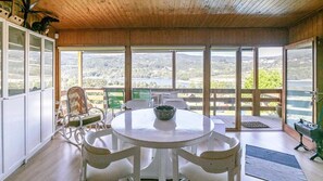 Quarto com uma mesa redonda, cadeiras, vista para o exterior e teto de madeira.