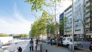 Eine moderne Stadtstraße mit Fußgängern, parkenden Autos und einem weißen Lastwagen.