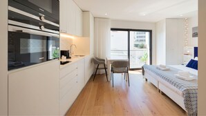 Una cucina moderna con un forno Siemens, una zona pranzo con tavolo e sedie, e una camera da letto con letto e balcone.