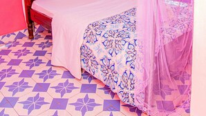 A bed with a canopy, a floral-patterned pillow, and a blue and white patterned bedspread.
