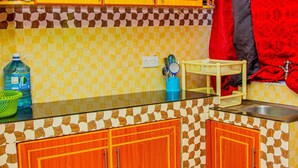 A kitchen with wooden cabinets, a tiled backsplash, and a red curtain.