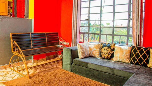 A room with a sofa, a bench, and a window with curtains.