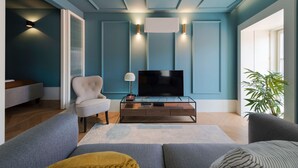Una sala de estar moderna con un televisor de pantalla plana, un sillón cómodo y un sofá.
