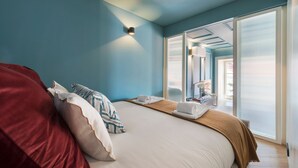 Un dormitorio con una cama grande, una colcha roja y vistas al exterior por una puerta corredera.
