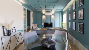 Una sala de estar moderna con una mesa de centro de vidrio, asientos cómodos, un televisor de pantalla plana y obras de arte enmarcadas en las paredes.