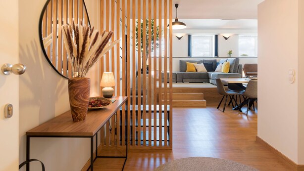 A modern living room with a sofa, dining area, and a decorative wooden partition. - Modern Loft w/ AC in Downtown Porto by LovelyStay (Porto)