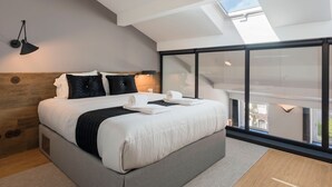 A modern bedroom with a large bed, a skylight, and a balcony with a view. - Modern Loft w/ AC in Downtown Porto by LovelyStay (Porto)