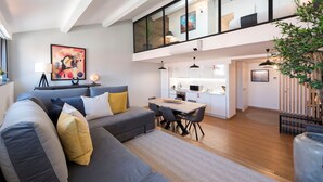 A modern living space with a grey sofa, a dining table, and a kitchen area. - Modern Loft w/ AC in Downtown Porto by LovelyStay (Porto)