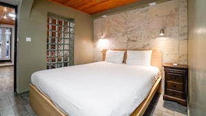 Ein Schlafzimmer mit einem großen Bett, einem Holzkopfteil, einer Marmorwand und einem kleinen Nachttisch mit Schubladen.
