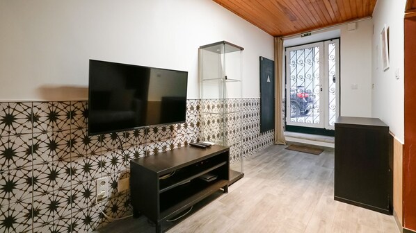 Una habitación moderna con televisión de pantalla plana en la pared, un aparador de vidrio y un mueble de madera.
