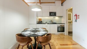 Una cocina compacta con electrodomésticos modernos, un comedor con una mesa redonda y cuatro sillas, y piso de madera.