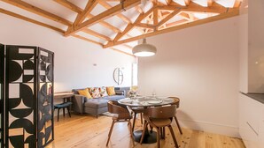 Un interior moderno con zona de comedor, un sofá y un separador decorativo.