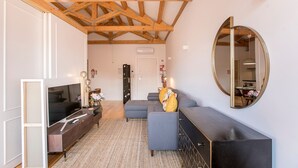 Una sala de estar moderna con televisor, sofá y un espejo grande.