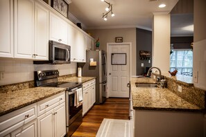 Features a double sink, refrigerator, and microwave, with ample natural light and recessed lighting.