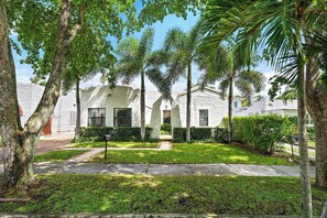 A residential area with a white building, palm trees, and a well-maintained lawn.