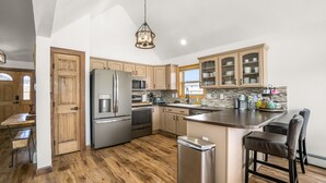 A modern kitchen with wooden cabinets, stainless steel appliances, and a central island. - Spacious Family Getaway, King Beds, Hot Tub, RMNP (Estes Park)